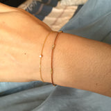 Wrist wearing tan silk bracelet with gold wire